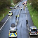 Drei verbeulte Autos auf einer Straße, die von Polizeifahrzeugen abgesperrt wird.