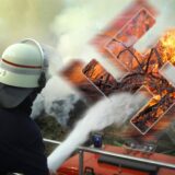 Ein Feuerwehrmann, der ein brennendes Hakenkreuz löschen. Eine Montage aus mehreren Bildern.