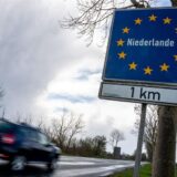 Ein Auto fährt an einem Schild vorbei, das auf die Grenze zu den Niederlanden hinweist.