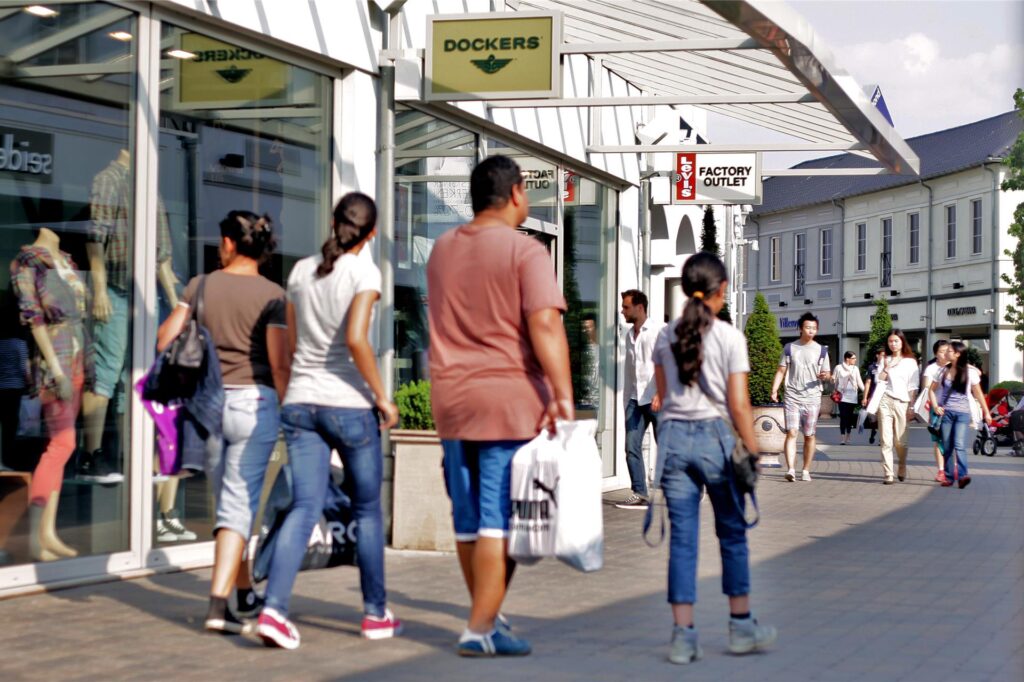 Besucher gehen im Designer Outlet Roermond an Geschäften vorbei.
