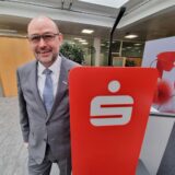 Ein Mann steht an einem Sparkassen-Schild