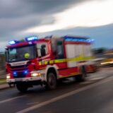 Ein Feuerwehrauto fährt mit Blaulicht über eine Straße.