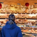 Ein Paar steht in einer Bäckerei vor der Ladentheke und schaut auf die Regale voller Backwaren. (Symbolbild)