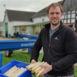 Jens Sanders mit Spargelstangen in der Hand auf seinem Hof in Henrichenburg.