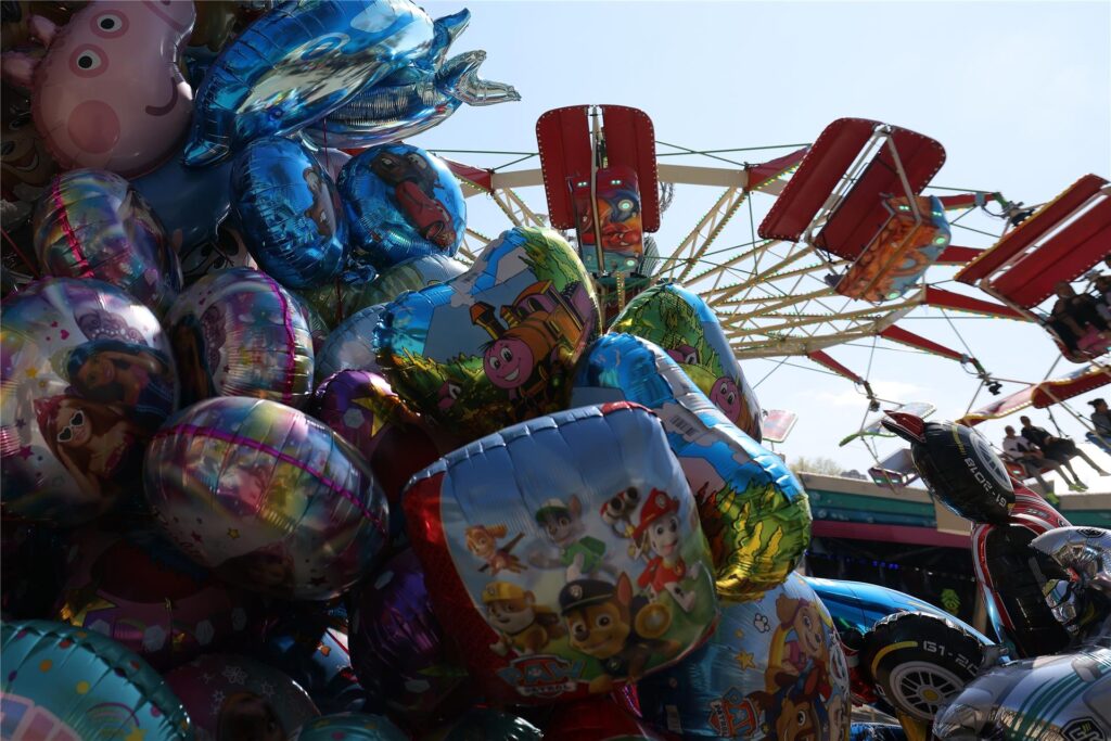 Mit Helium befüllte bunte Ballons sind auf der Osterkirmes in Düsseldorf-Grafenberg vor einem Fahrgeschäft zu sehen.