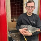 Junger Mann mit einem Huhn auf dem Arm