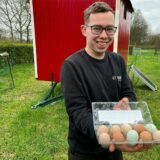 Junger Mann mit Eiern in Plastikschale