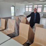 Ein Mann steht an gestapelten Stühlen und Tischen