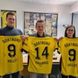 Drei Personen halten BVB-Trikots hoch.
