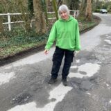 Sandra Baumann zeigt auf Schlaglöcher in der Speckhorner Straße in Recklinghausen.
