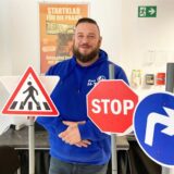 Fahrlehrer Sven Holzmann steht neben verschiedenen Verkehrschildern.