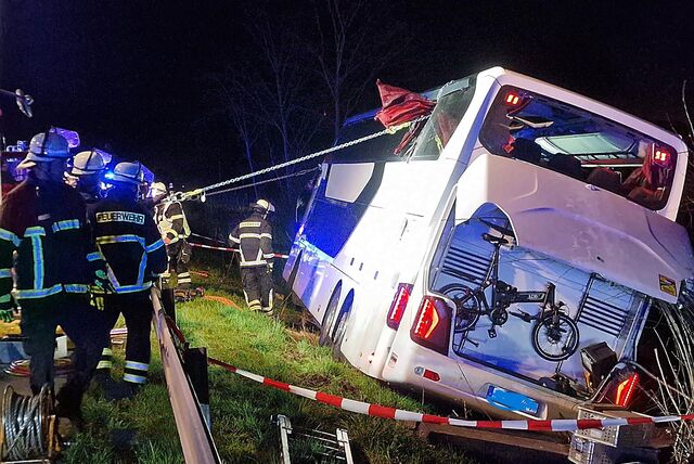 Feuerwehrleute richten den auf der A44 umgekippten Bus mit Gurten wieder auf.