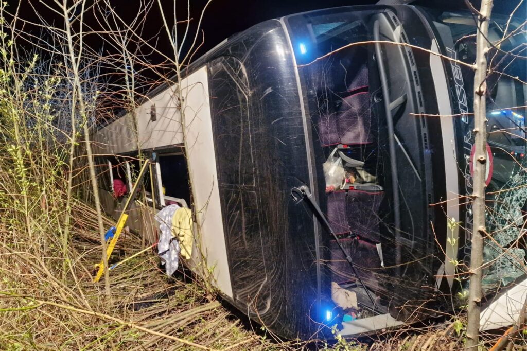 Der Bus ist auf der A44 bei Werl auf die Beifahrerseite gekippt und kam neben der Fahrbahn zum Stehen. Das Fahrzeug ist schwer beschädigt. Die Notausstiege am Dach sind geöffnet.