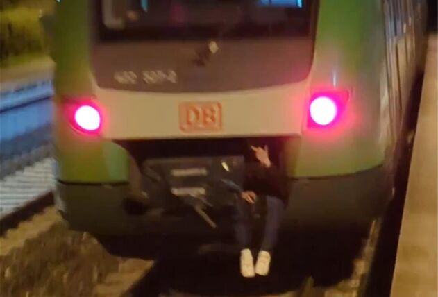 Ein Jugendlicher fährt an der Zugkupplung einer S-Bahn mit.