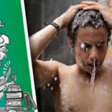 Junger Mann steht unter der Dusche.