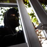 Ein Vermummter hebelt ein Fenster auf.