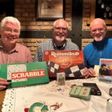 Drei Männer zeigen Spiele in die Kamera.