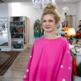Eine Frau steht in einem Modegeschäft und schaut in die Kamera.