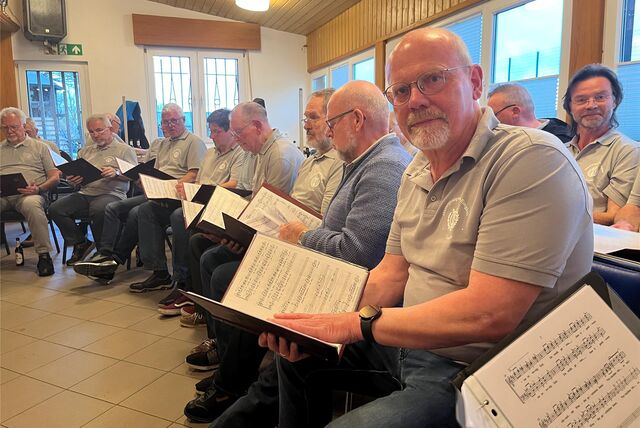 Männerkreis mit Notenblättern vor sich
