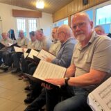 Männerkreis mit Notenblättern vor sich