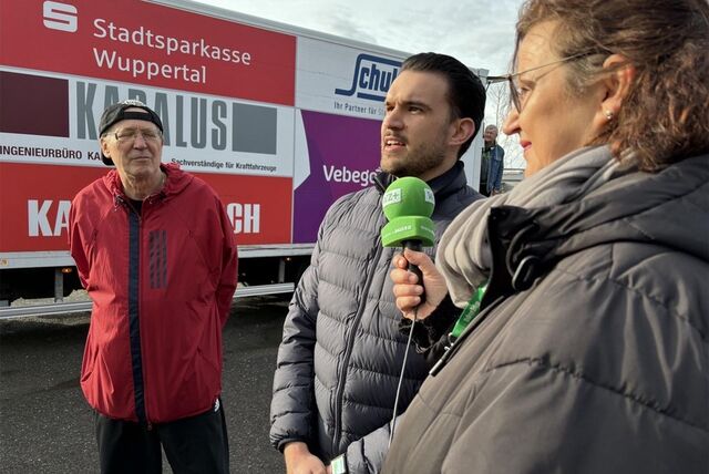 Eine Frau steht mit einem Mikrofon der Waltroper Zeitung neben zwei Gesprächspartnern. Im Hintergrund ist ein Lkw zu erkennen.