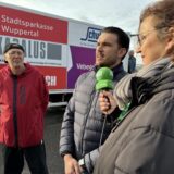 Eine Frau steht mit einem Mikrofon der Waltroper Zeitung neben zwei Gesprächspartnern. Im Hintergrund ist ein Lkw zu erkennen.