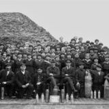 Historisches Bild der Wasag-Belegschaft von 1918 – Männer und Frauen in dunkler Kleidung mit Hüten oder Kopftüchern