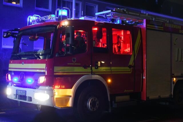 Ein Feuerwehrwagen steht mit Blaulicht in einer Straße.