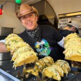 Ein Mann zeigt Tacos in die Kamera.