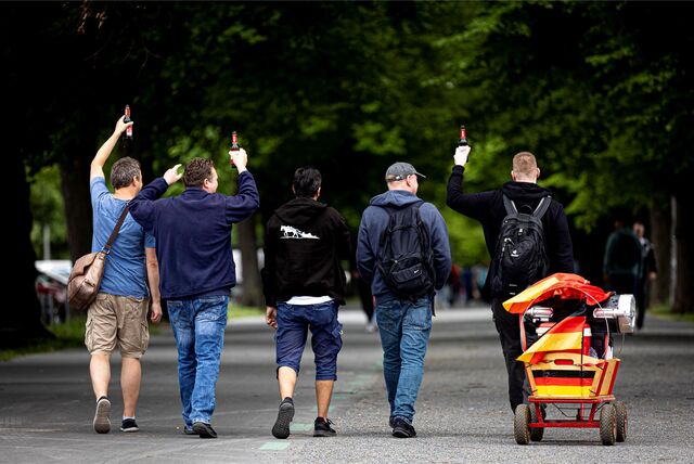 Männer gehen am Vatertag mit einem Bollerwagen einen Weg entlang.