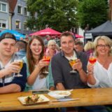 Gäste des Feierabendmarktes prosten sich zu.