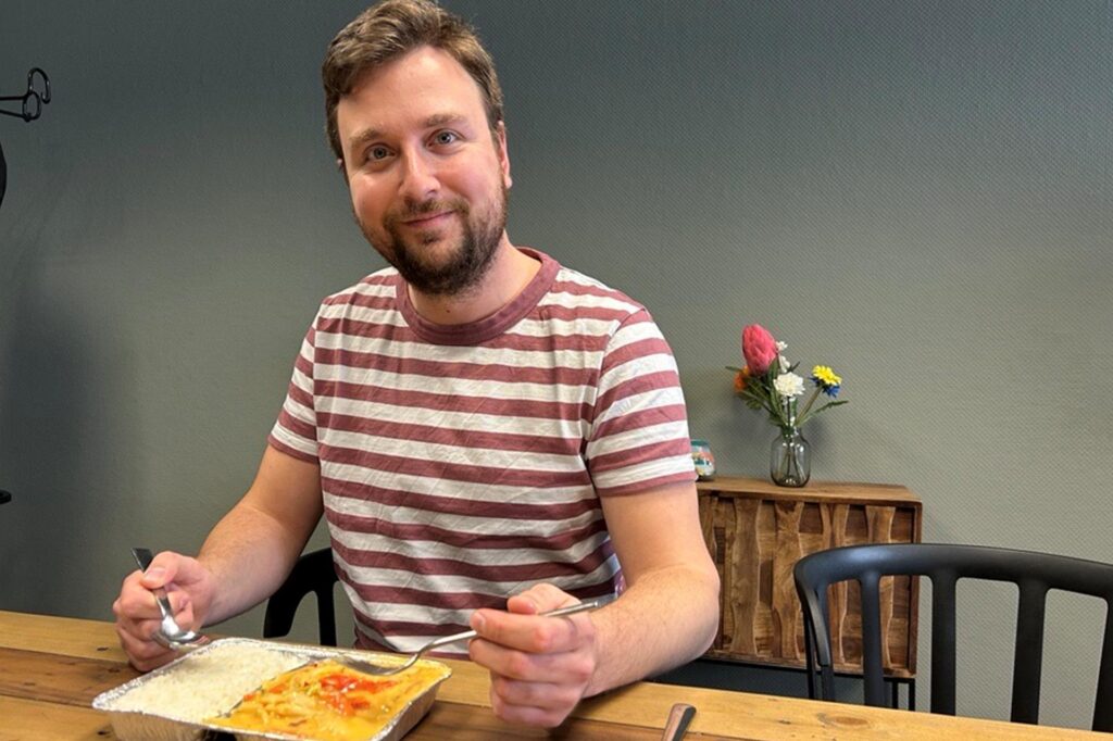 RN-Redakteur Philipp Thießen sitzt an einem Tisch und isst ein Gericht von RN-Redakteur Philipp Thießen sitzt an einem Tisch und isst ein Gericht von