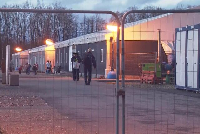 Mitarbeiter eines Sicherheitsdienstes und Bewohner der Notunterkunft in der Abenddämmerung.