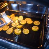 Zitronenscheiben liegen in einem Backofen und werden mit Wasser übergossen.