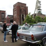 Auf dem Gelände der Zeche Ewald in Herten-Süd stehen einige Oldtimer. Vor den Fahrzeugen stehen Menschen, die auf die Fahrzeuge blicken oder sich unterhalten.