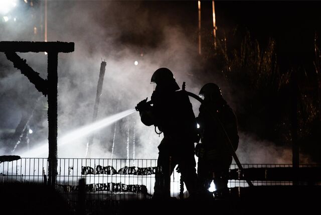 Zwei Feuerwehrleute löschen in Herten-Scherlebeck ein Feuer in einem Carport.