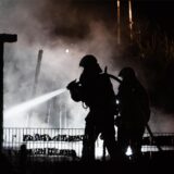 Zwei Feuerwehrleute löschen in Herten-Scherlebeck ein Feuer in einem Carport.