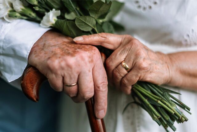Hände eines alten Ehepaares. Der Mann trägt den Ehering an der rechten, die Frau an der linken Hand.