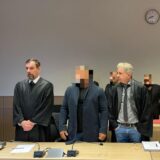 Angeklagte und Verteidiger stehen in einem Gerichtssaal.