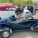 Ein Mann blickt beim Oldtimertreff der Motorworld Ruhr auf dem Gelände der Zeche Ewald in ein ausgestelltes Cabrio.