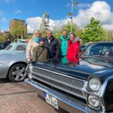 Eine Familie steht zwischen den ausgestellten Oldtimern. Im Hintergrund sind Gebäude der Zeche Ewald in Herten-Süd zu sehen.