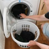 Ein Mann holt Wäsche aus der Waschmaschine.