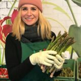Anna Caspari hält frischen grünen Spargel in den Händen.