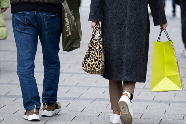 Ein Mann und eine Frau gehen in der Innenstadt mit Einkaufstüten durch die Fußgängerzone.