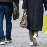 Ein Mann und eine Frau gehen in der Innenstadt mit Einkaufstüten durch die Fußgängerzone.