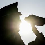 Ein Polizist schaut durch ein Lasermessgerät