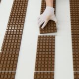 Ein Mitarbeiter des Schokoladenherstellers Ritter Sport kontrolliert Schokoladentafeln.