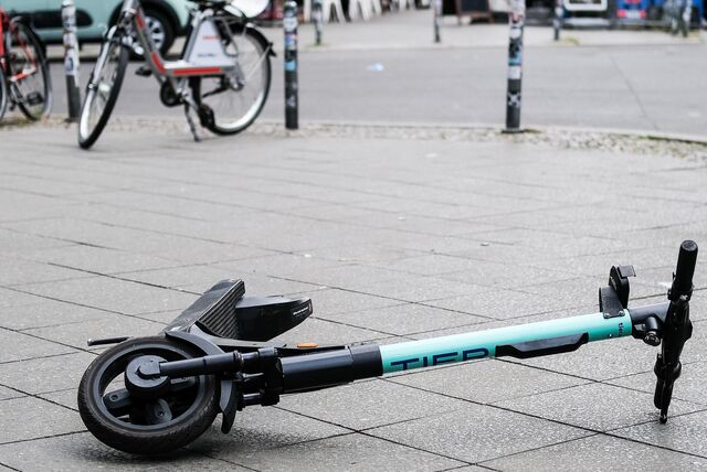 Liegen gebliebener Leih-E-Scooter in mintgrün auf einem Gehweg.