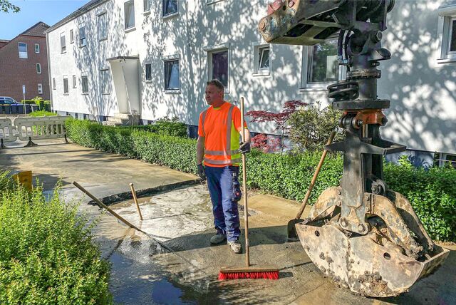 Ein Mann steht neben einer Baugrube, die voller Wasser ist.