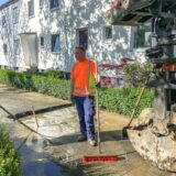 Ein Mann steht neben einer Baugrube, die voller Wasser ist.